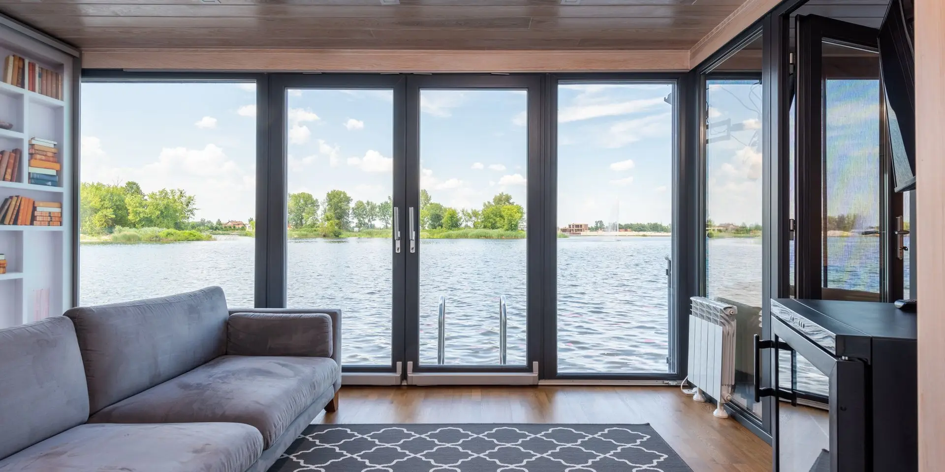 Living room with floor-to-ceiling windows overlooking a lake, the kind of view many Bloomfield Hills homes are built around