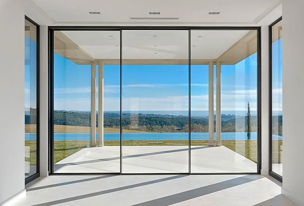 Floor-to-ceiling slim aluminium sliding glass doors with a lake view, suited to Traverse City homes